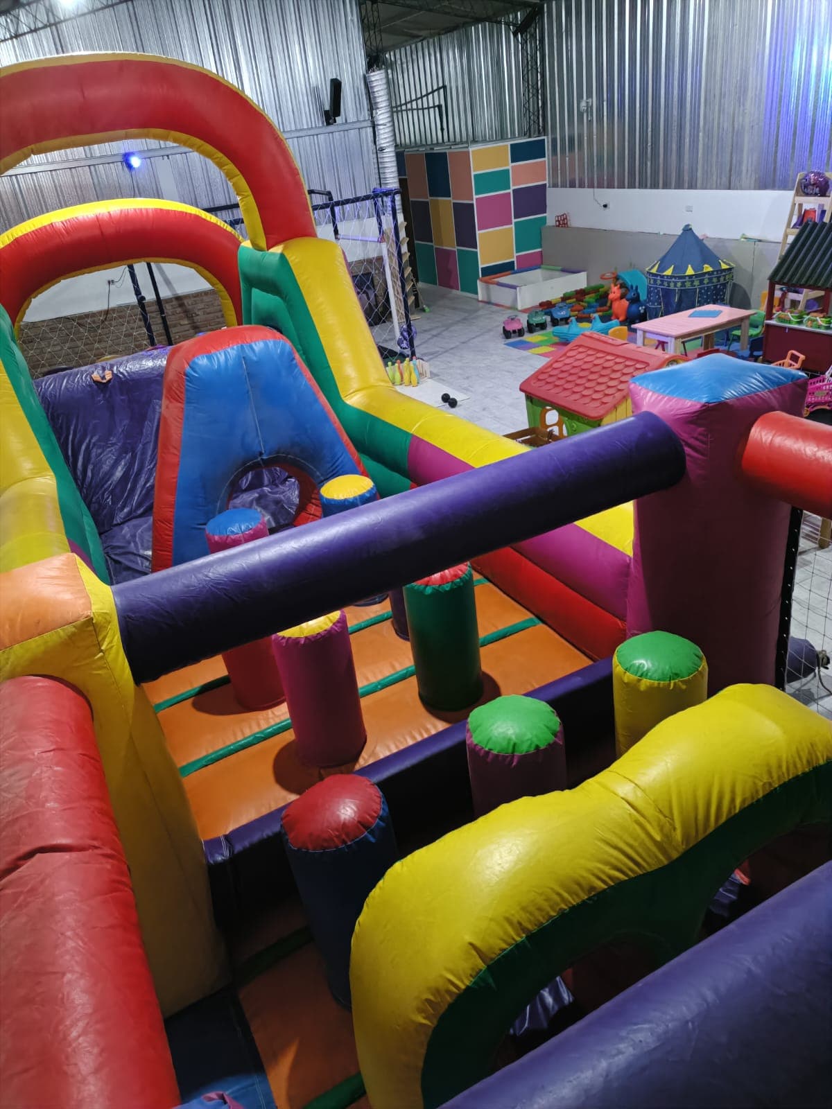 Parque inflable multicolor con obstáculos y toboganes en un centro de recreación para niños.