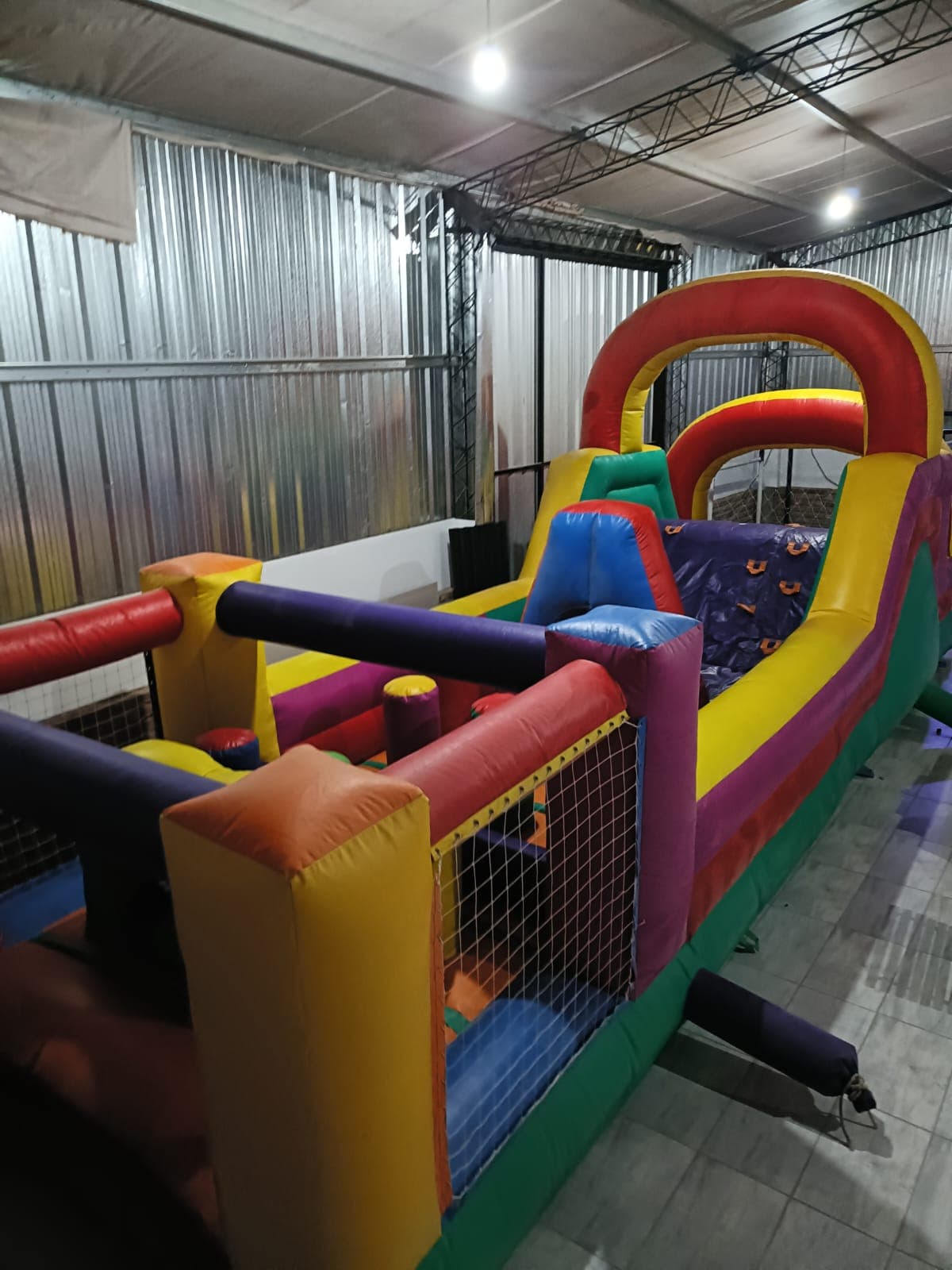 Circuito de obstáculos inflable y colorido con arcos y túneles dentro de un gran almacén.